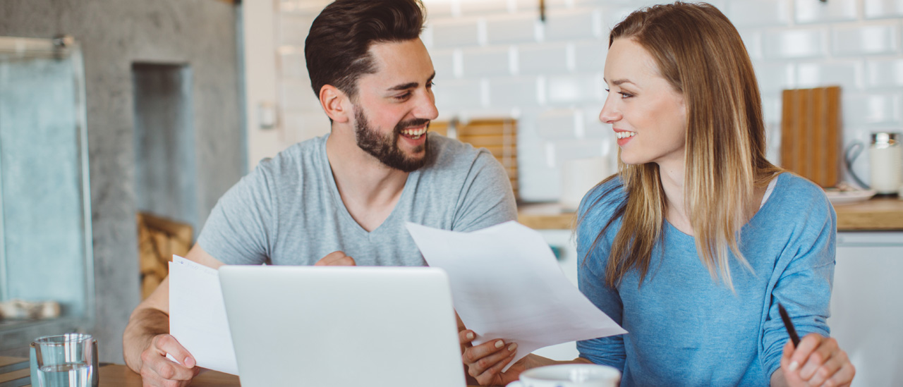 A couple reviewing paper work in front of a laptop